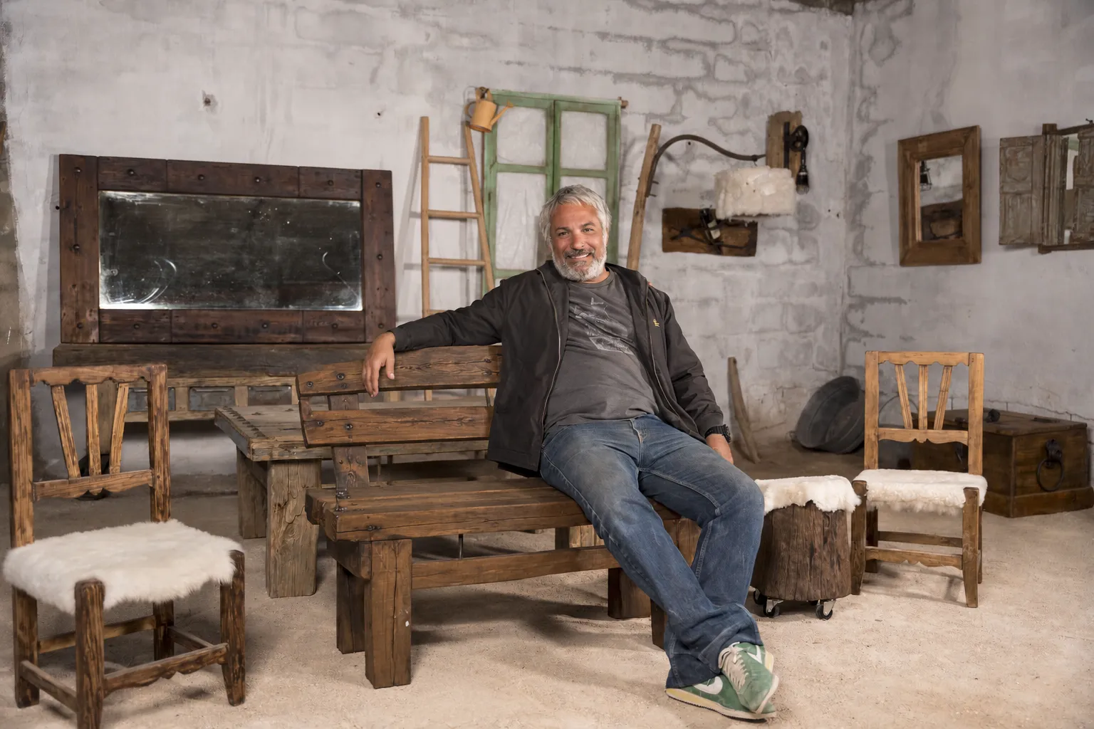 Alejandro González sentado entre muebles de madera en su taller de Aguas Nuevas