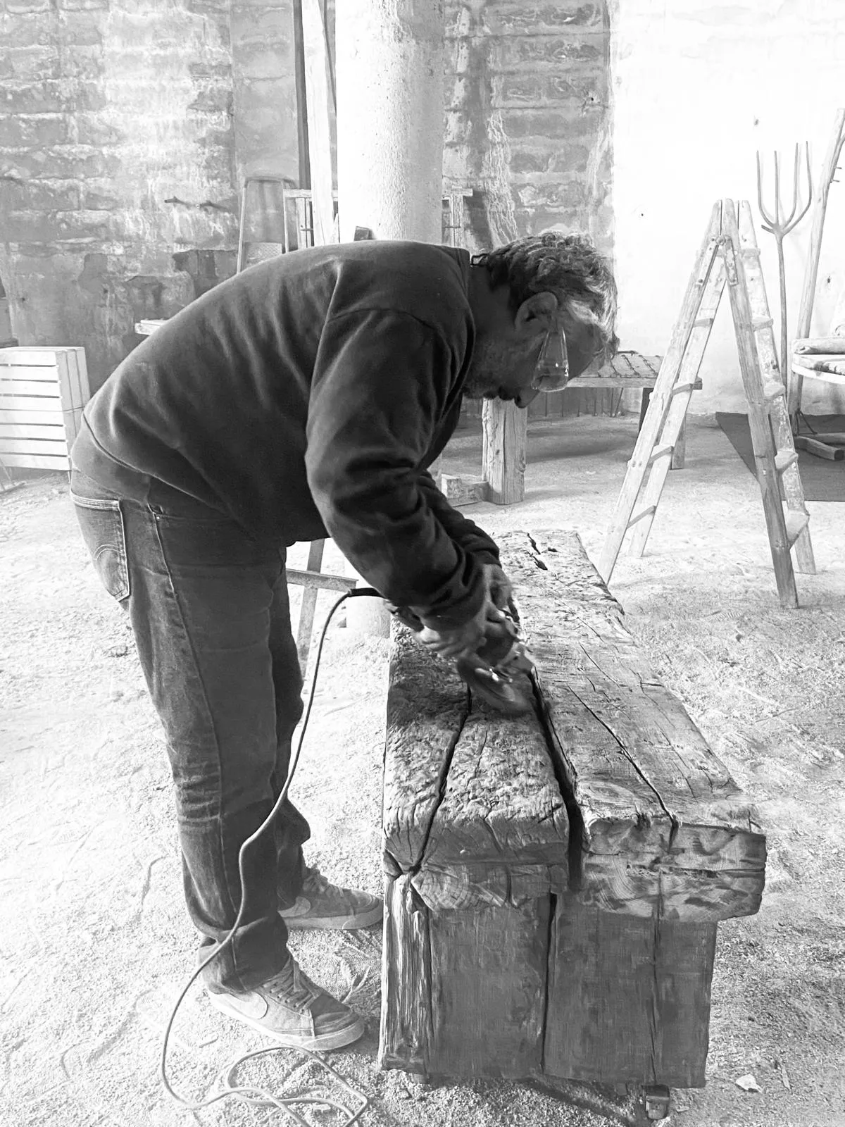 Alejandro González trabaja una pieza de madera recuperada con una amoladora en su taller