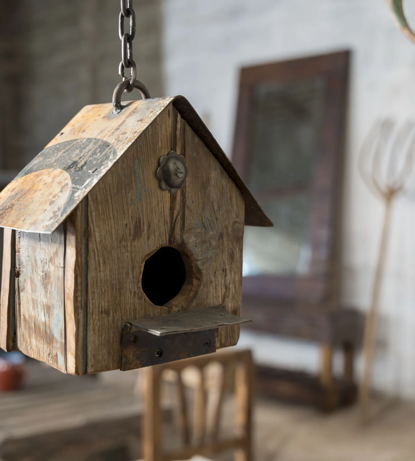 Casita de pájaros de madera recuperada con tejado de chapa, colgada de una cadena