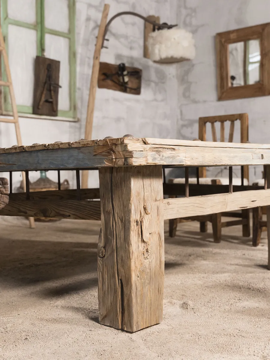 Mesa de tachuelas con canto azul en el taller, entre sillas de madera