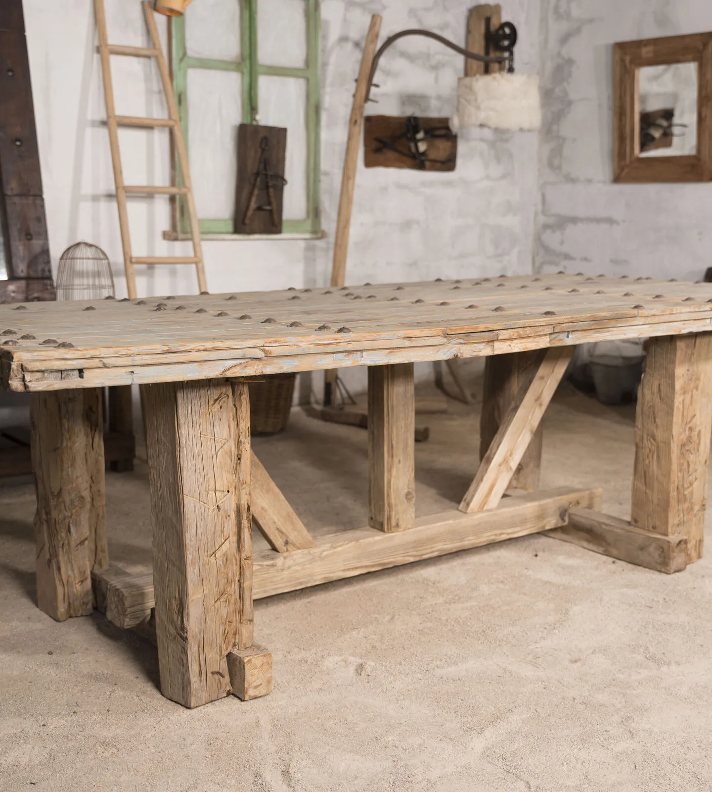 Mesa de comedor de madera recuperada con patas en caballete y tablero claveteado
