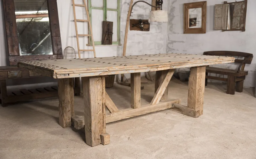 Mesa de comedor de madera recuperada con patas en caballete y tablero claveteado